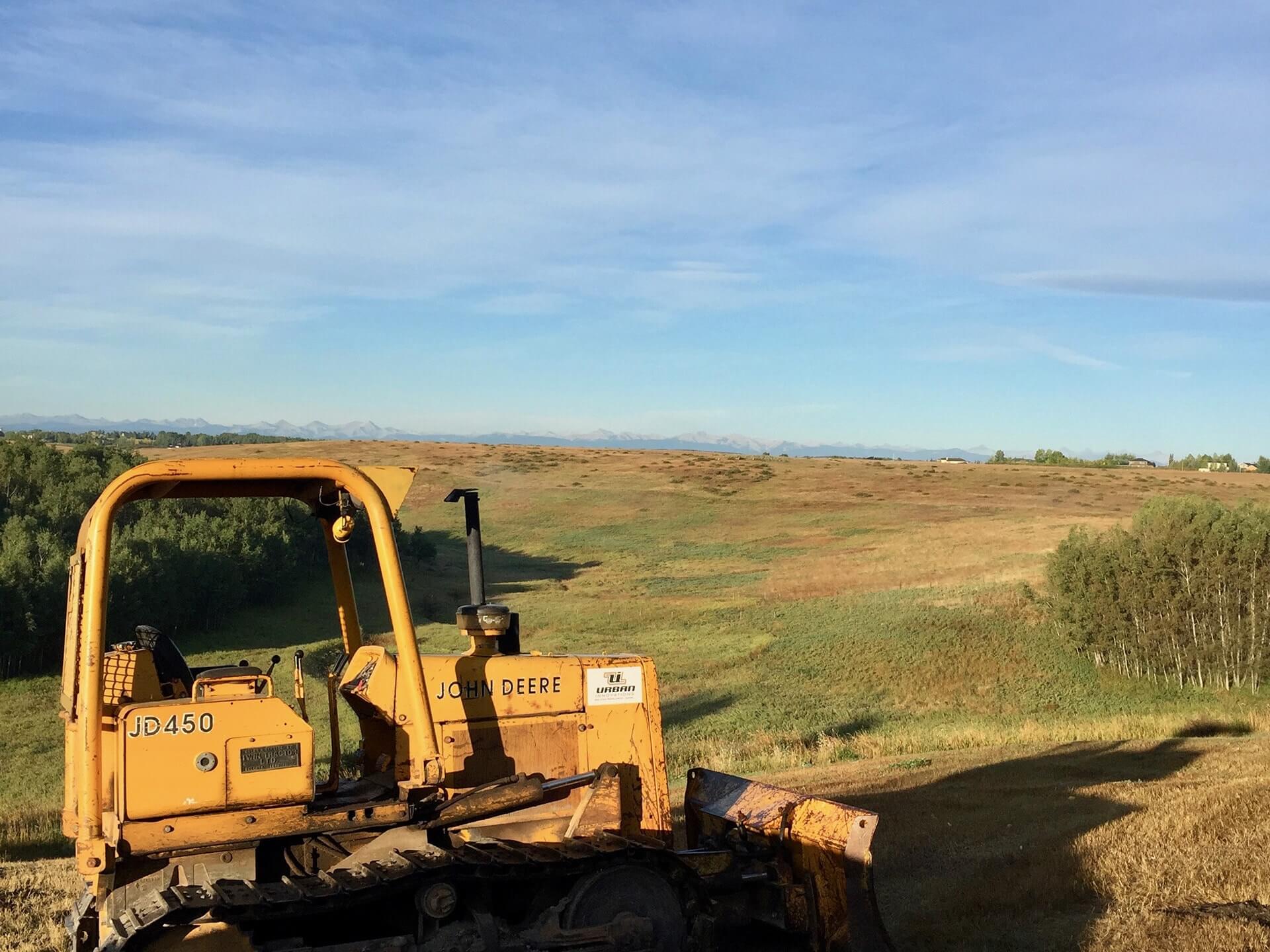 A vintage John Deere tractor sits atop a hill of grass