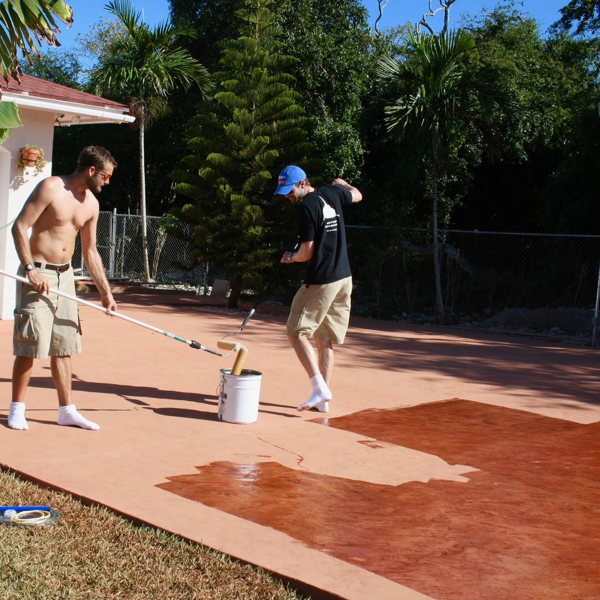 Two workers at Freehold Concrete work to seal a new stamped concrete driveway. The contrast of colours and beauty of the project shows through as the sealer is applied.