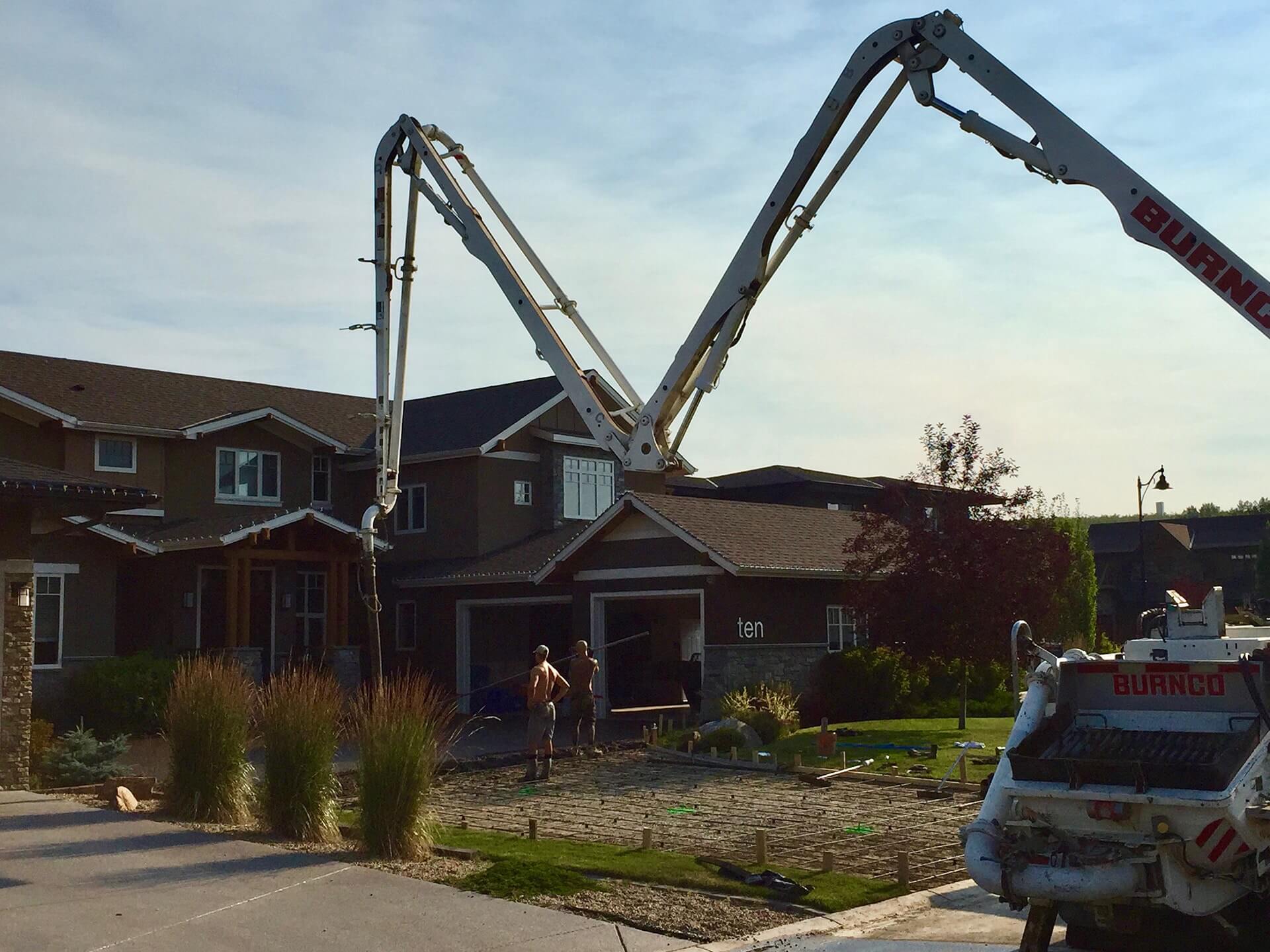 a concrete boom pump is extended and setup to place concrete into a large driveway.