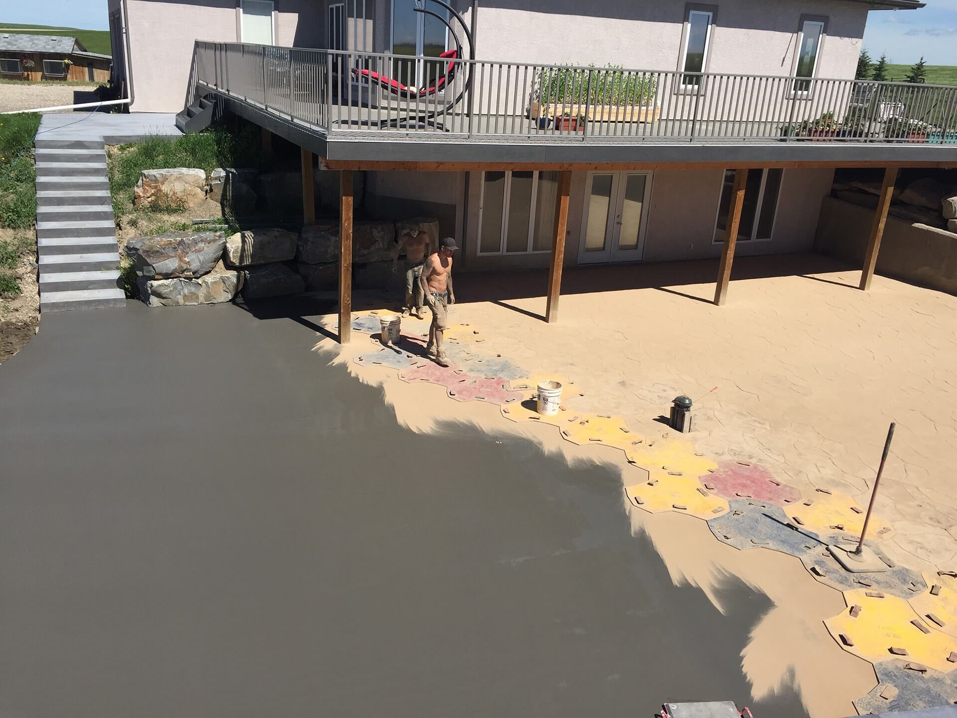 A concrete finisher works to spread coloured powder and impression fresh concrete.