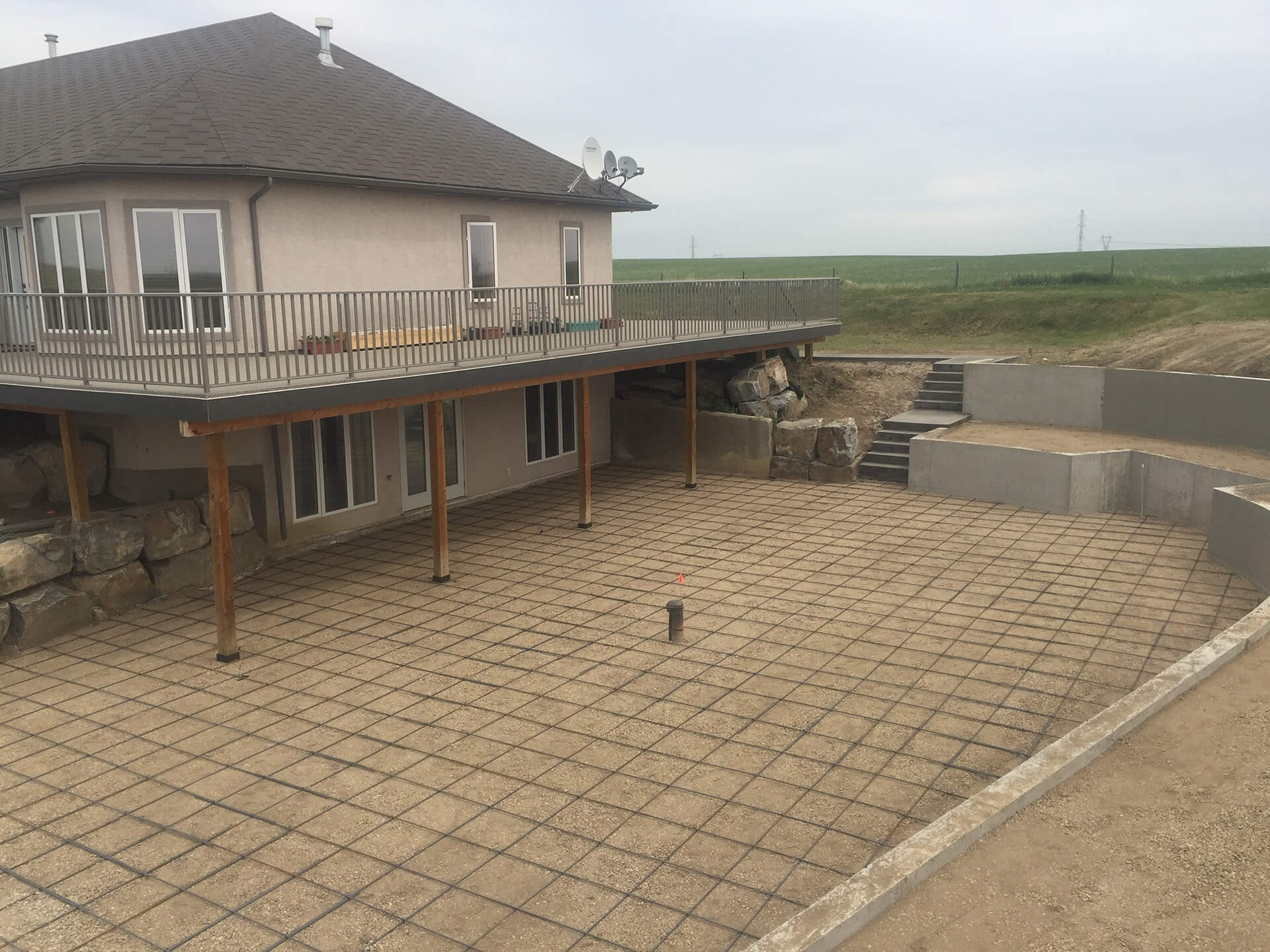 A large patio area with a well laid rebar grid awaits concrete. Retaining walls surround the area with a concrete staircase.