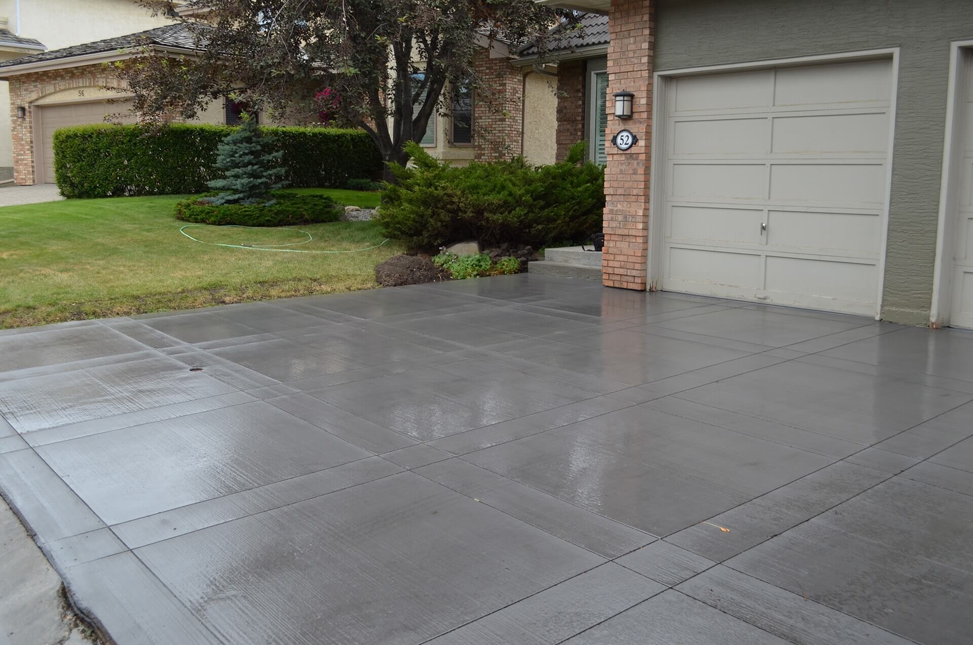 a black brushed finish driveway has a decorative saw cut pattern in it.