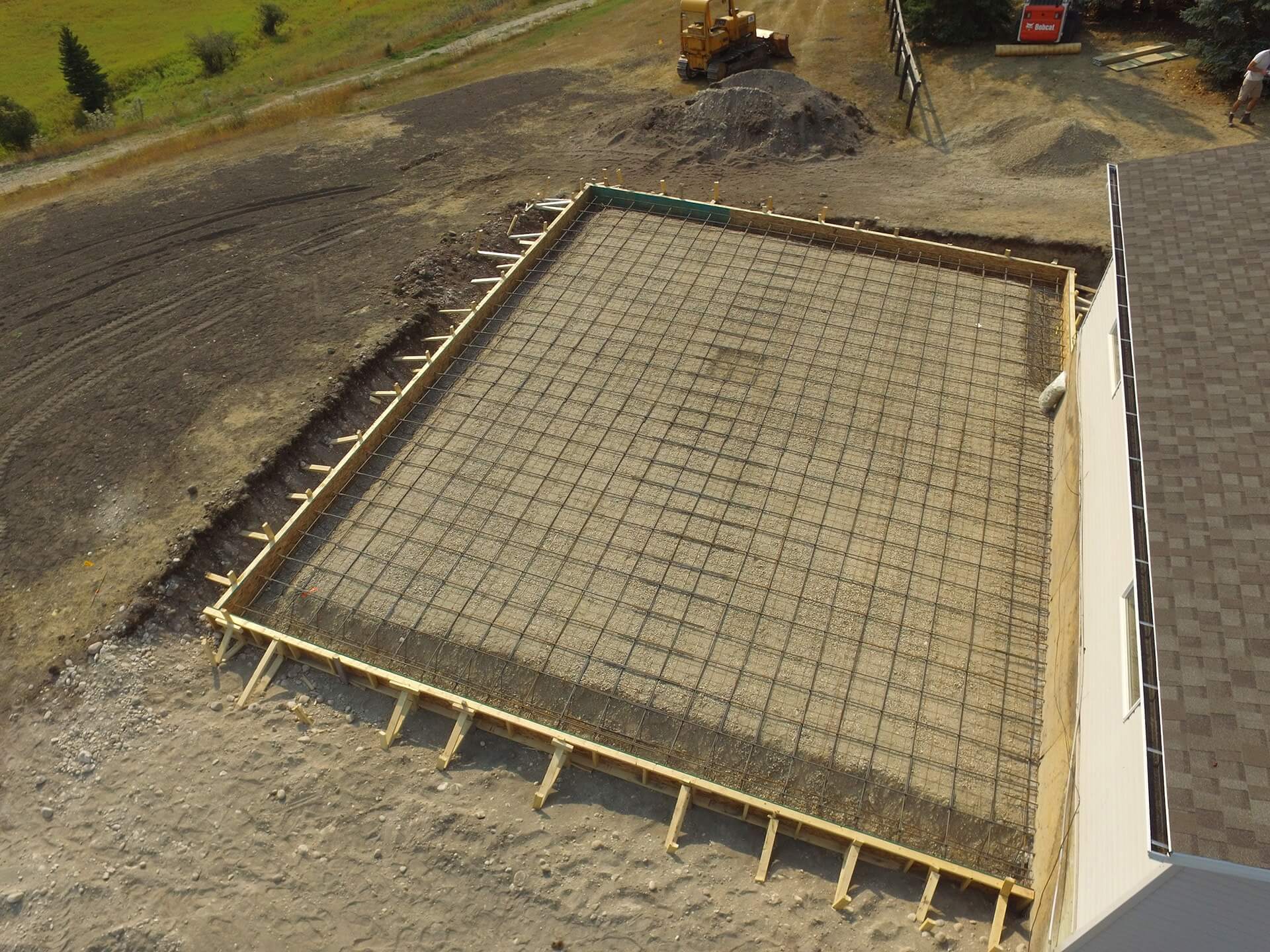 aerial drone shot of engineered garage foundation. Plywood walls and rebar grid await concrete.