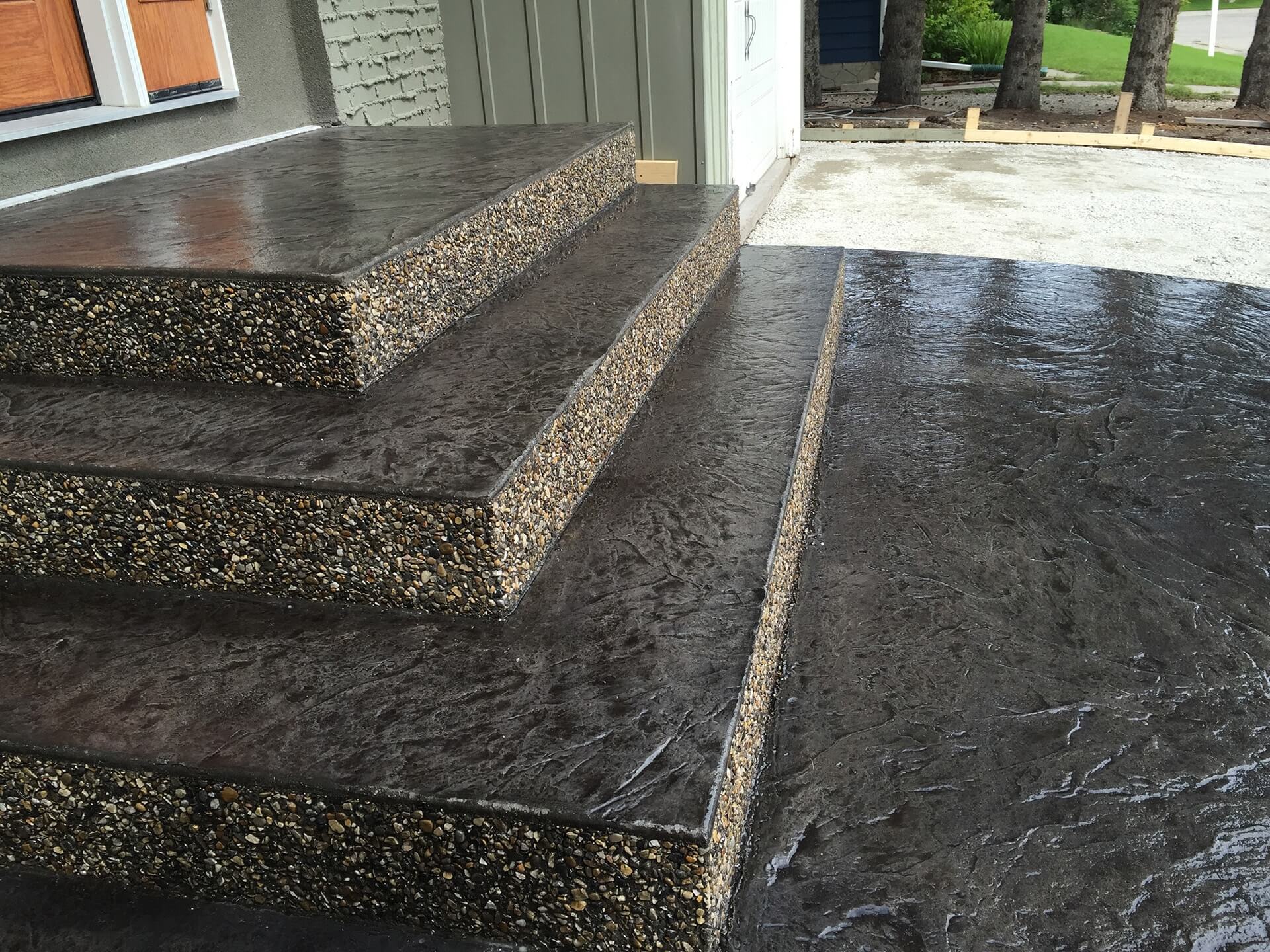 A front step with three risers is shown with a beautiful finish of slate stamped concrete with exposed aggregate vertical faces.
