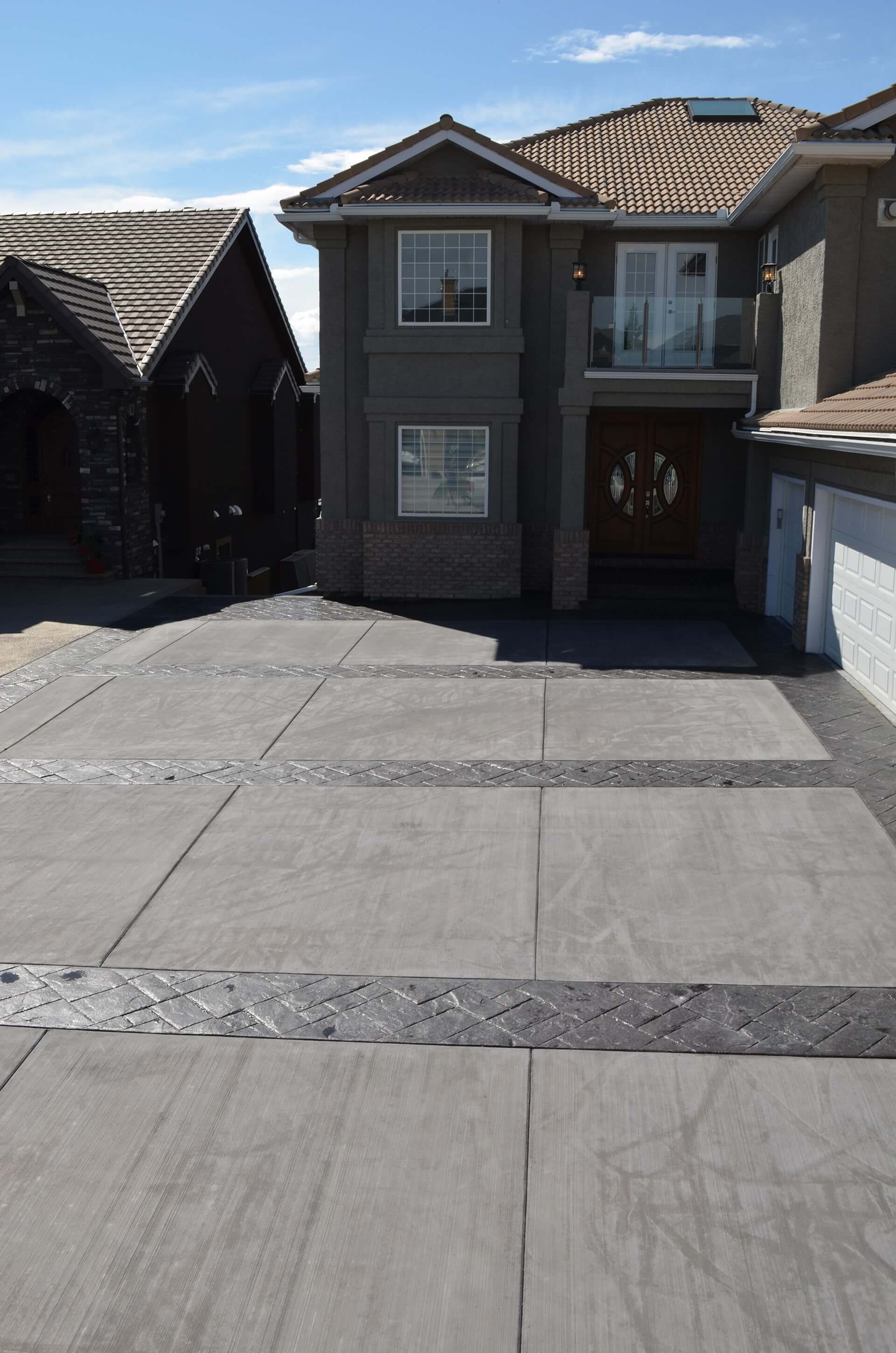a decorative driveway with sealed stamped borders and broom finish inserts. Lines are visible on the broom finish areas from blanket curing the driveway.