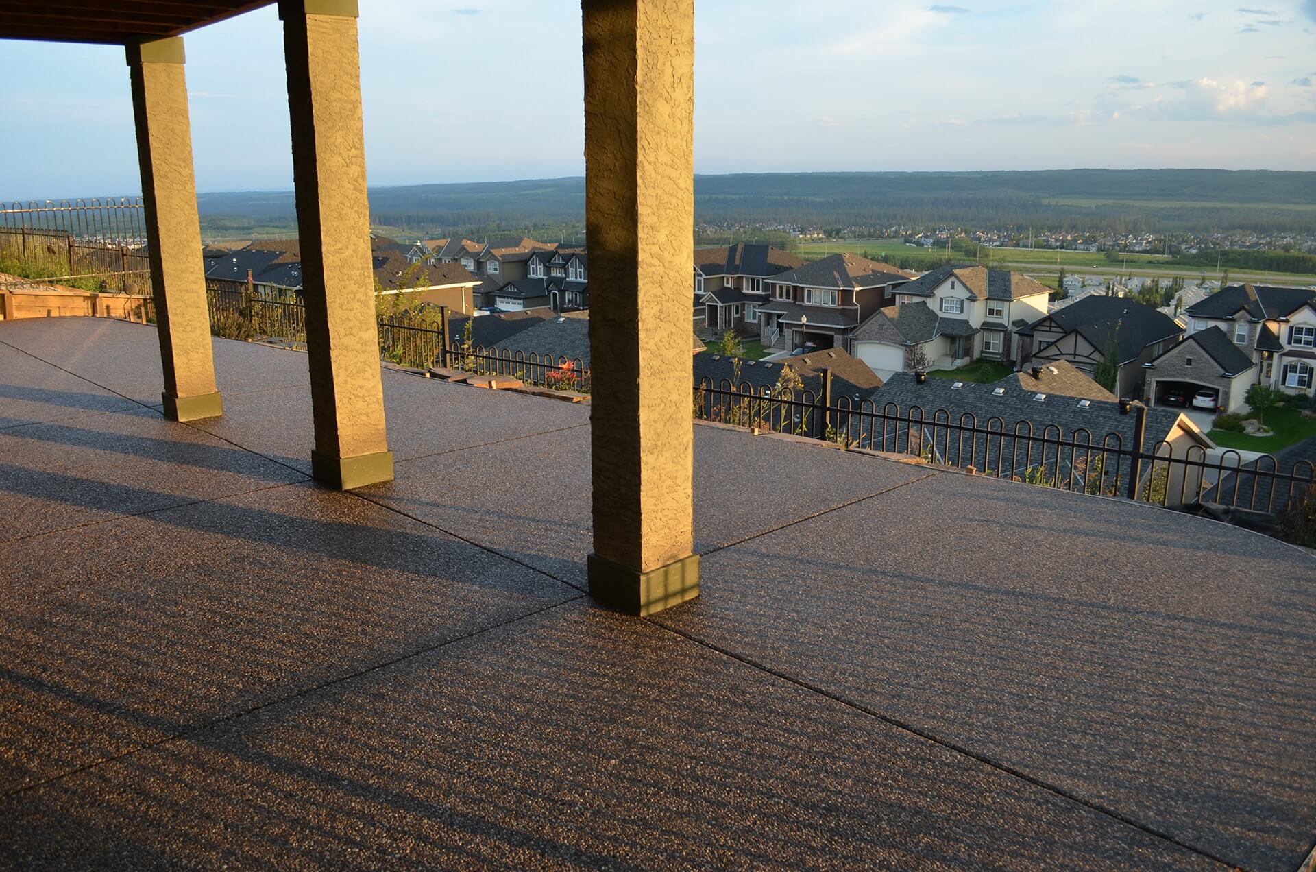 a black exposed aggregate patio surrounds supporting deck pillars on a ridge view patio.