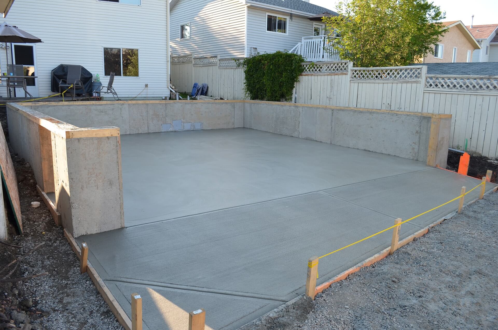 An engineered garage foundation has been freshly completed. Four foot tall foundation walls surround a new floor and brushed concrete apron.