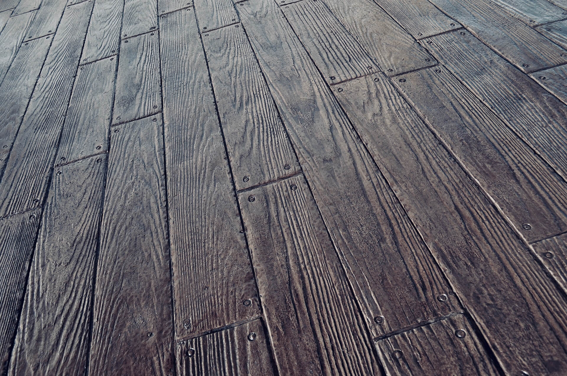 stamped concrete that has been hand stained and textured to appear like wooden boards.